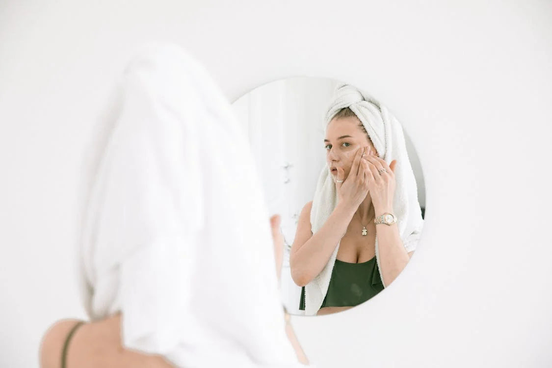 A woman looking in a mirror and applying face cream